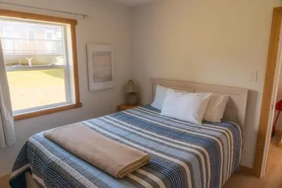 a bedroom with a bed with a striped blanket and a window at Little Beach Resort in Ucluelet