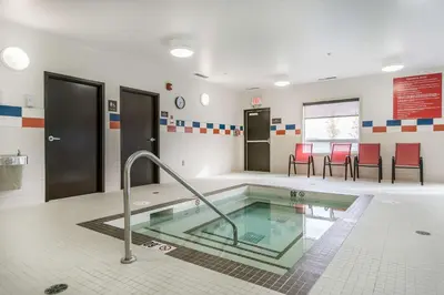 a hot tub in a room with red chairs at Comfort Inn & Suites Edmonton International Airport in Nisku