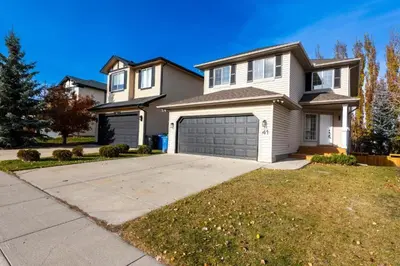 a large white house with a garage at Valley Home 2 Bed 1 Bath Walkout Basement Apartment, 1hr to Banff, 40 Mins Canmore, 5 mins to WinSport & Olympic park in Calgary