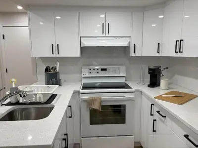 a white kitchen with white cabinets and a sink at Valley Home 2 Bed 1 Bath Walkout Basement Apartment, 1hr to Banff, 40 Mins Canmore, 5 mins to WinSport & Olympic park in Calgary