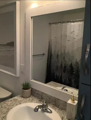 a bathroom with a sink and a mirror with a window at City Center Olive Grove in Kamloops