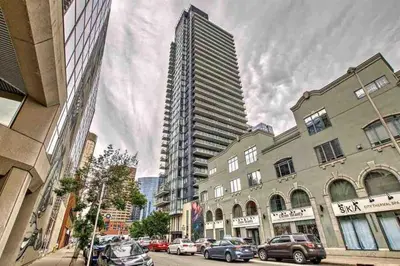a tall building on a city street with parked cars at MicroNest - Modern Overlooking Downtown Parking in Calgary