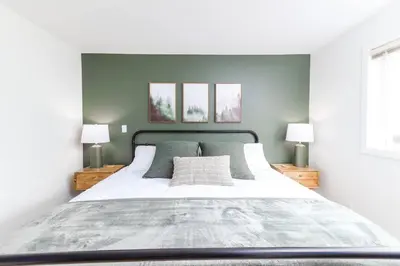 a bedroom with a large white bed with two lamps at Wintergreen Retreat w/Hot Tub by Village in Kelowna
