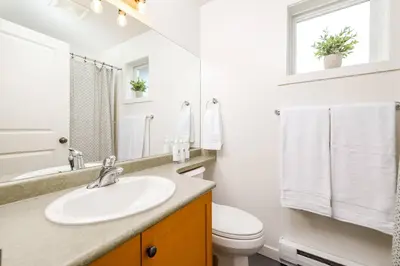 a white bathroom with a sink and a toilet at Wintergreen Retreat w/Hot Tub by Village in Kelowna