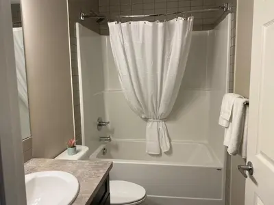 a bathroom with a tub and a toilet and a sink at Mahogany's Comfy Haven in Calgary