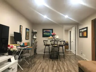 a living room with a desk and a table with chairs at Dolly's Deluxe Suite in Fort Saskatchewan