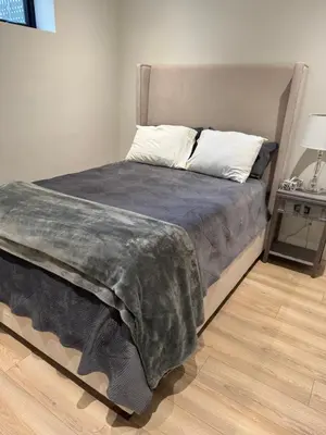 a bed with a gray blanket and a side table at Delux 2 bedroom suite in White Rock