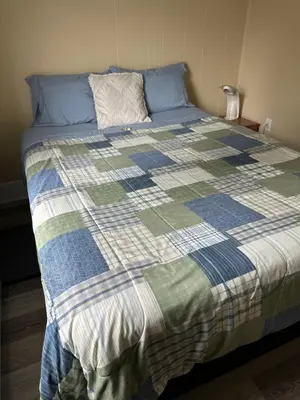a bed with a blue and green quilt on it at Sweet Home Alert Bay in Alert Bay