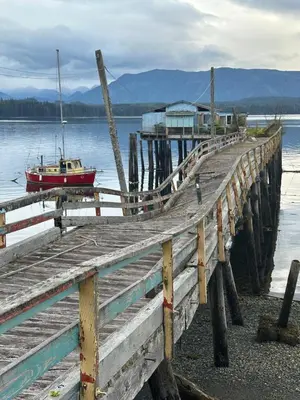 a wooden pier with a boat on the water at Sweet Home Alert Bay in Alert Bay