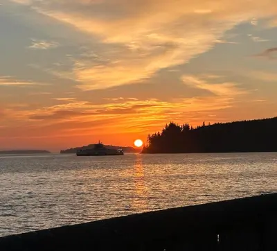 a boat in the water with a sunset in the background at Sweet Home Alert Bay in Alert Bay