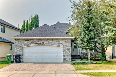 a house with a white garage door in a yard at cozy two bedrooms with external bathroom just for you in Calgary