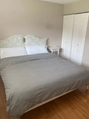 a bedroom with a large bed with white sheets at Large suite with separate access in Richmond