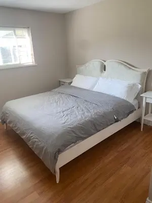 a bedroom with a large bed with a wooden floor at Large suite with separate access in Richmond