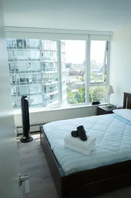 a bedroom with a bed and a large window at Center of the City in Vancouver