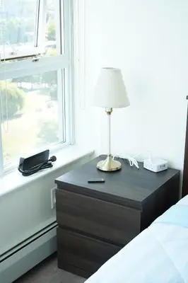 a nightstand with a lamp on it next to a window at Center of the City in Vancouver