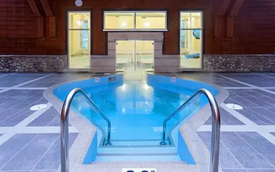 a swimming pool in a building with stairs in it at Cozy Canmore resort with mt view hot tub and pool in Canmore