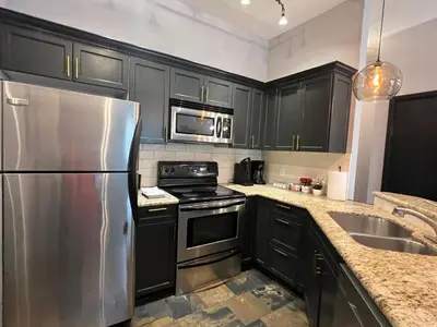a kitchen with black cabinets and a stainless steel refrigerator at Cozy Canmore resort with mt view hot tub and pool in Canmore