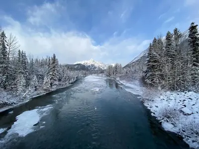 a river covered in snow with a mountain in the background at Cozy Canmore resort with mt view hot tub and pool in Canmore