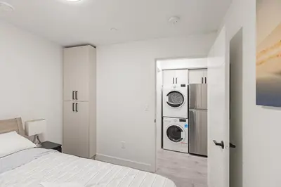 a bedroom with a bed and a washer and dryer at Dumfries Guest Room in Vancouver in Vancouver