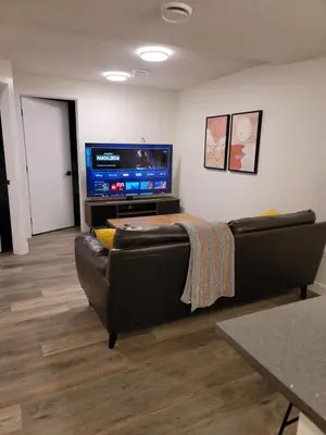 a living room with a couch and a flat screen tv at Lovely Modern 2 Bedroom Basement Suite in Edmonton