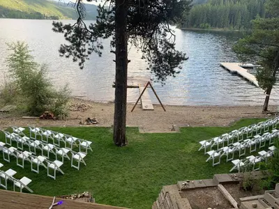 a bunch of chairs sitting on the grass by a lake at Beachfront Lake House Moyie BC in Moyie
