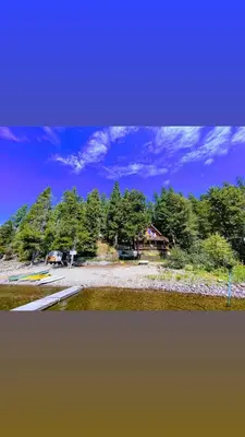 a view of a beach with trees in the background at Beachfront Lake House Moyie BC in Moyie