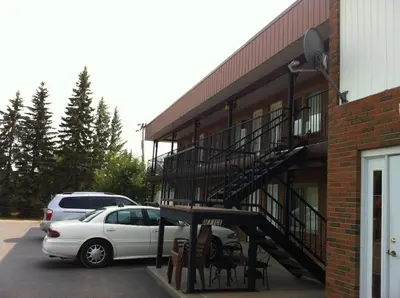 a white car parked in a parking lot next to a building at Rest Easy Motel in Three Hills