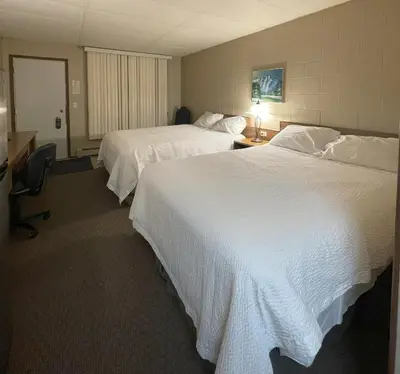 a hotel room with two beds and a desk at Rest Easy Motel in Three Hills