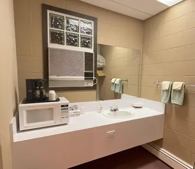 a bathroom with a sink and a microwave at Rest Easy Motel in Three Hills