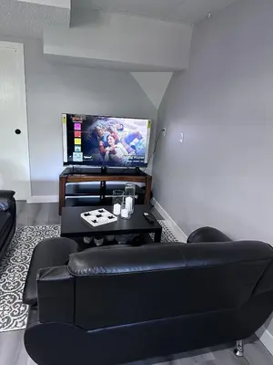 a living room with a black couch and a tv at Valley Gateway in Calgary