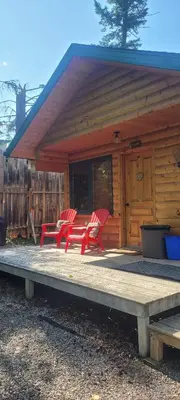 a cabin with red chairs on a wooden deck at Beautiful Cabin near Radium Hot Springs with private hot tub in Radium Hot Springs