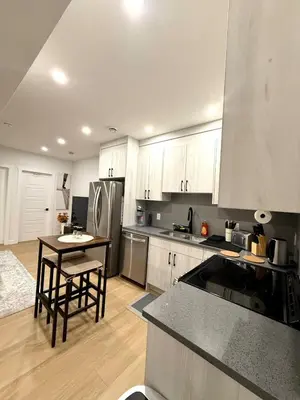 a kitchen with white cabinets and a table and a refrigerator at Luxe Stay with a Designer Touch in Calgary