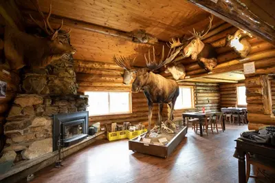 a room with a fireplace with a statue of a moose in it at Tatogga Lake Resort in Iskut