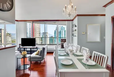 a dining room with a table and chairs and a television at Luxury 2BR Designer Apartment In The Heart Of Downtown! in Vancouver