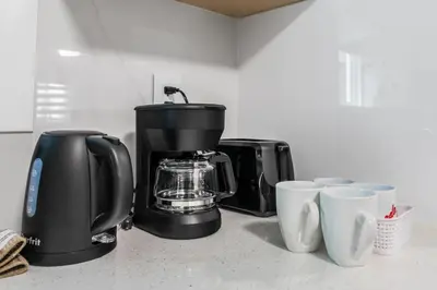 a kitchen counter with a coffee maker and coffee cups at A cozy and stylish 2-bedroom retreat in Surrey