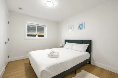 a bedroom with a bed with white sheets and a window at A cozy and stylish 2-bedroom retreat in Surrey