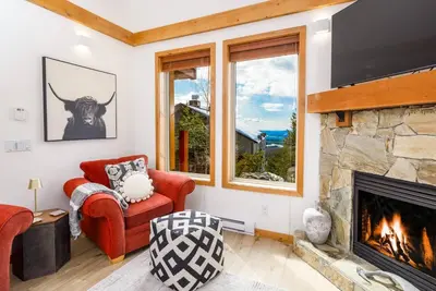 a living room with a fireplace and a red chair at Perfection South 1 in Big White