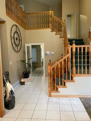 a living room with a staircase and a clock on the wall at The HI-Mark House - Hot tub,AC,Pool table, Pool May2026 in Sicamous