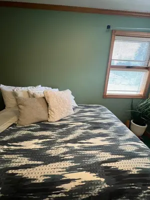a bed with a black and white comforter and a window at The HI-Mark House - Hot tub,AC,Pool table, Pool May2026 in Sicamous