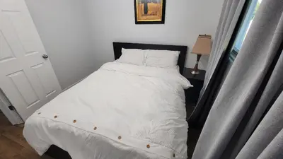 a bed with white sheets and pillows next to a window at 3 Bedroom House Near Airport and Downtown in Calgary