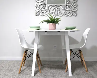 a white table with two chairs and a plant on it at Apartment In Calgary Near Airport in Calgary