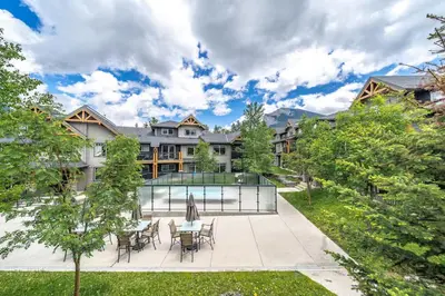 a mansion with a pool and tables and chairs at Best 2BR Canmore Stay, Banff, Wifi & Free Parking Incl in Dead Man's Flats