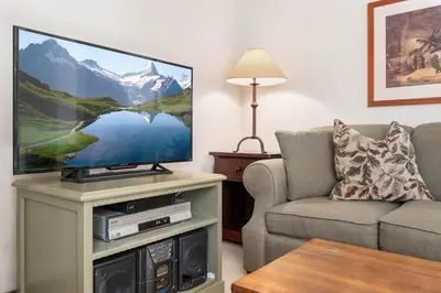 a living room with a flat screen tv on a table at 1BR and Sofabed in Marquise, Near Ski Hill, Fireplace, Hot Tub and Sauna, Gym Access in Whistler