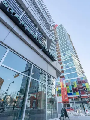 a tall glass building with a sign in front of it at Urbanest - Spectacular Views & Amenities Parking in Calgary