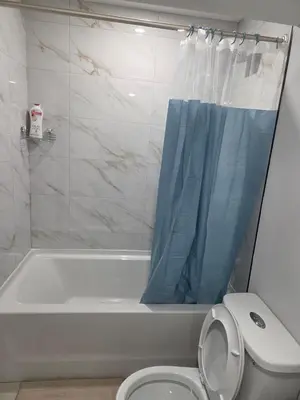 a bathroom with a tub and a toilet with a blue shower curtain at Exclusive Suite in Edmonton in Edmonton