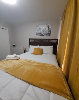 a bedroom with a large white bed with yellow curtains at Spacious Basement Suite NW Calgary- 1bedroom 2 guest maximum in Calgary