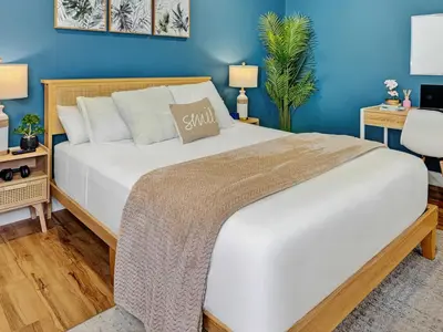 a bedroom with a large white bed with blue walls at Private Studio - 5 Min to DT - Self Check-In - 75 Inch TV in Williams Lake