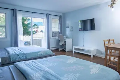 a bedroom with two beds and a desk and a television at The Driftwalk Walkable to Beach in Harrison Hot Springs