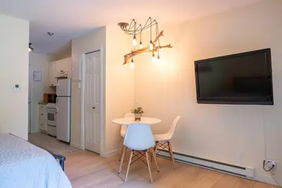 a room with a table and a tv on a wall at Studio w Balcony with Smart TV and 2 Min Walk to Lake in Harrison Hot Springs