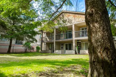 a large building with a tree in front of it at RiversTail Retreat Pet-Friendly and Steps to The Lake in Harrison Hot Springs